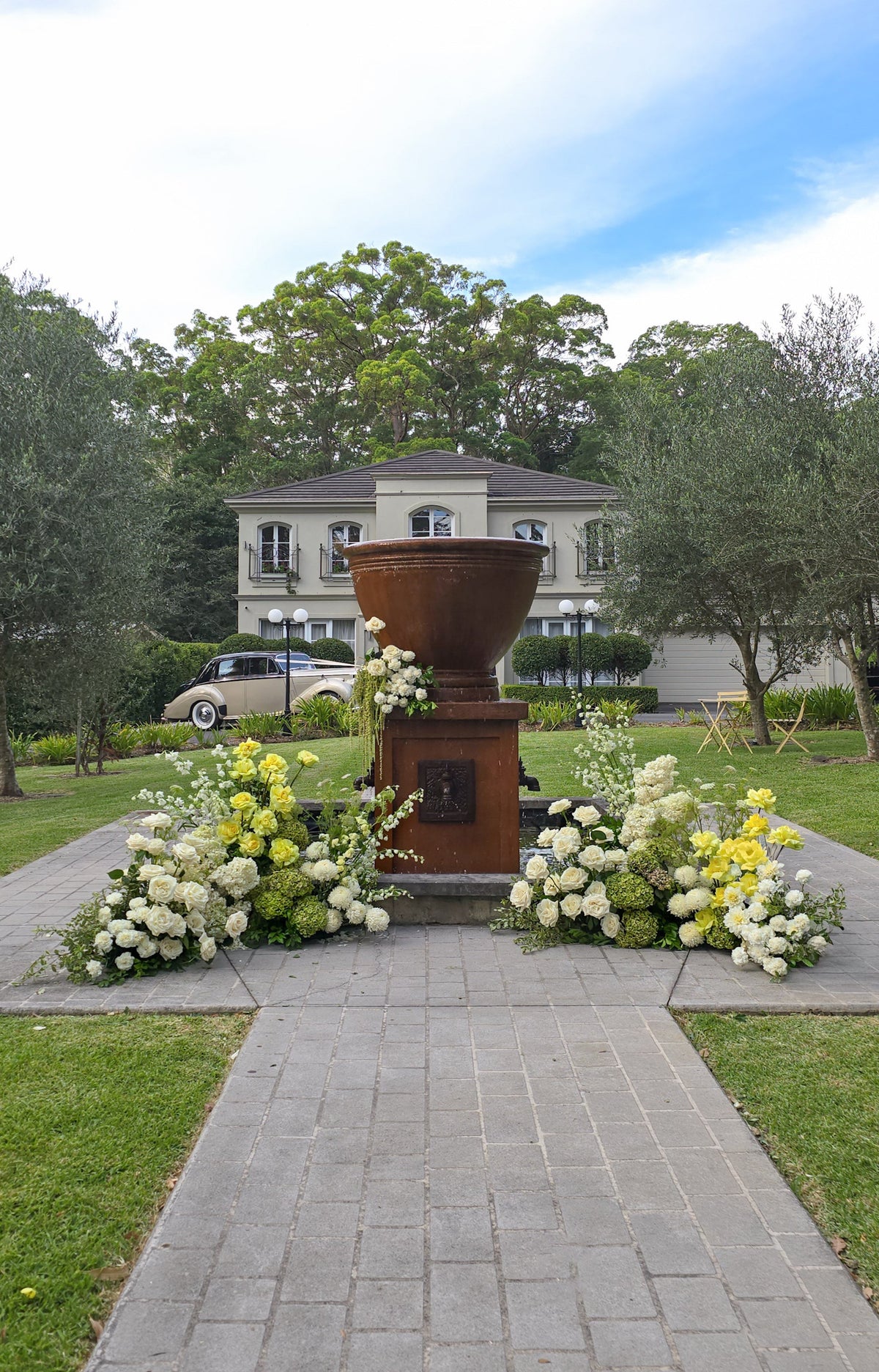 Decorative urn with flowers on a stone pathway in front of a house